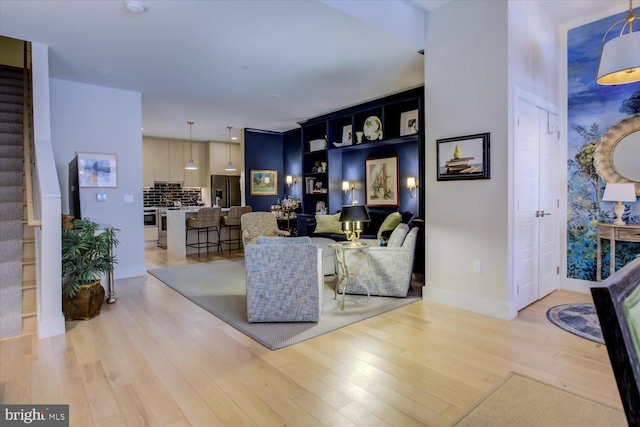 living room featuring light wood-style flooring, stairs, and baseboards