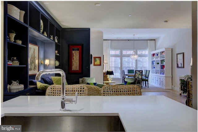 kitchen featuring open shelves, light countertops, an inviting chandelier, open floor plan, and dark cabinetry