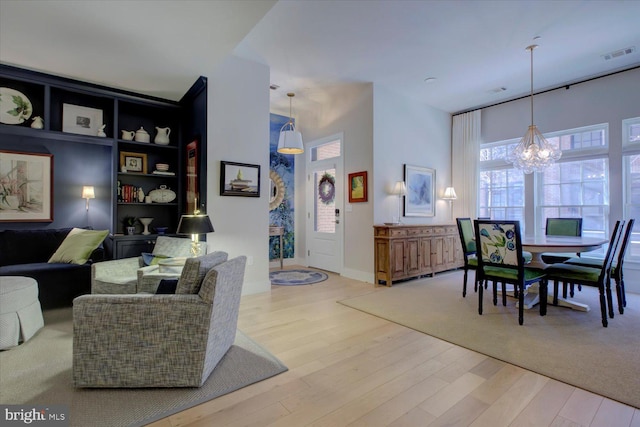 living room featuring a chandelier, wood finished floors, and visible vents