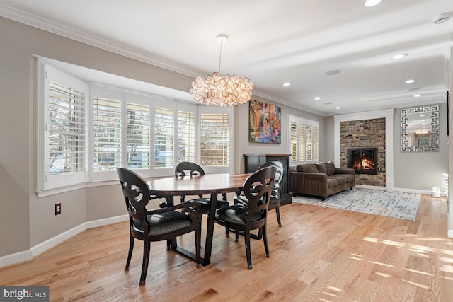 dining room with ornamental molding, light hardwood / wood-style floors, and a brick fireplace