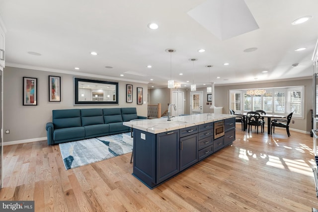 kitchen featuring sink, a spacious island, stainless steel microwave, ornamental molding, and decorative light fixtures