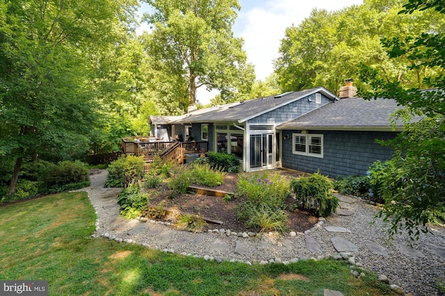 rear view of house featuring a wooden deck and a yard