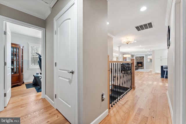 corridor with ornamental molding, a chandelier, and light hardwood / wood-style flooring