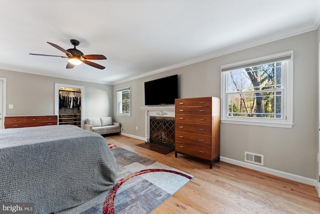 bedroom with ceiling fan, ornamental molding, light hardwood / wood-style floors, and a closet