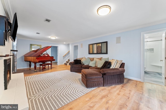 living room featuring ornamental molding, a fireplace, and light hardwood / wood-style floors