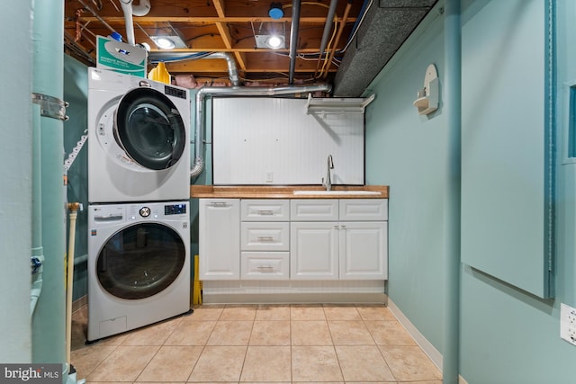 laundry area featuring stacked washer and dryer, sink, cabinets, and light tile patterned floors