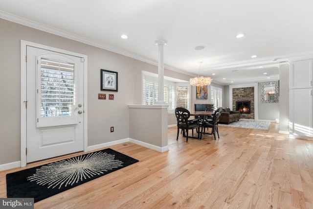 foyer entrance featuring crown molding, a large fireplace, and light wood-type flooring