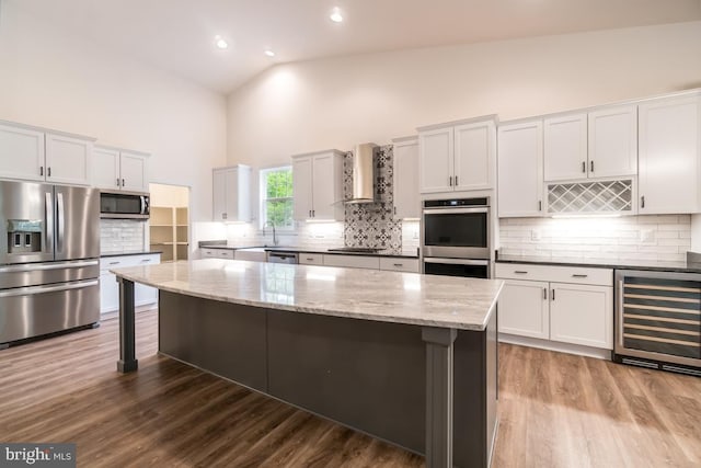 kitchen featuring wine cooler, appliances with stainless steel finishes, high vaulted ceiling, and wall chimney range hood