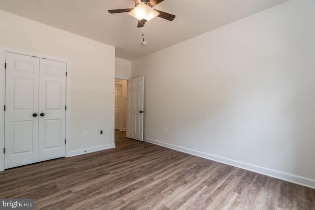 unfurnished bedroom with dark hardwood / wood-style flooring, ceiling fan, and a closet