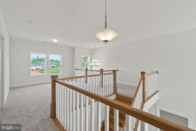 hallway featuring an inviting chandelier and carpet floors