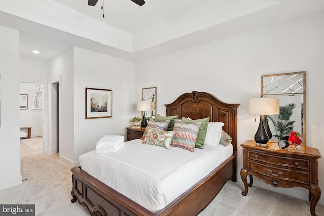 carpeted bedroom featuring ceiling fan and a tray ceiling