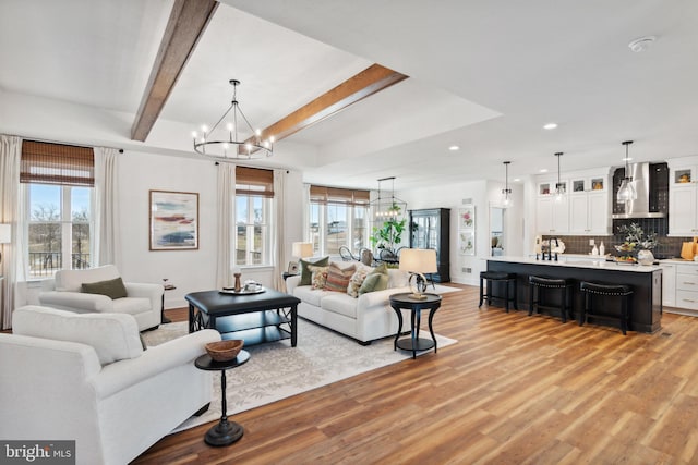 living room featuring an inviting chandelier, light hardwood / wood-style floors, and beamed ceiling