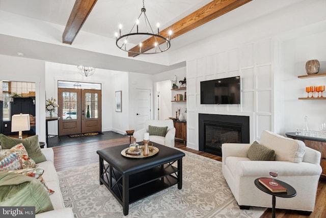 living room with wood-type flooring, an inviting chandelier, and beam ceiling