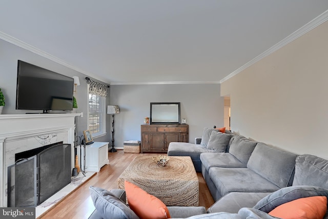 living room with a high end fireplace, ornamental molding, and light hardwood / wood-style floors