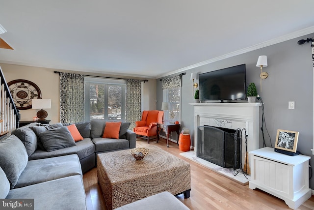 living room featuring ornamental molding, a fireplace, and light hardwood / wood-style floors