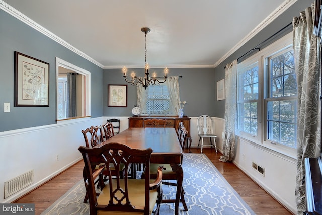 dining area featuring hardwood / wood-style flooring, crown molding, and a notable chandelier