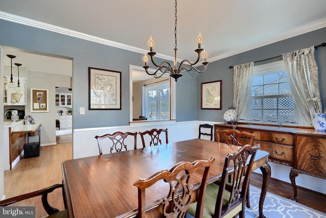 dining space with ornamental molding, a chandelier, and light hardwood / wood-style floors