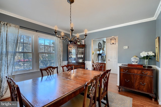 dining space featuring wood-type flooring, ornamental molding, and a chandelier