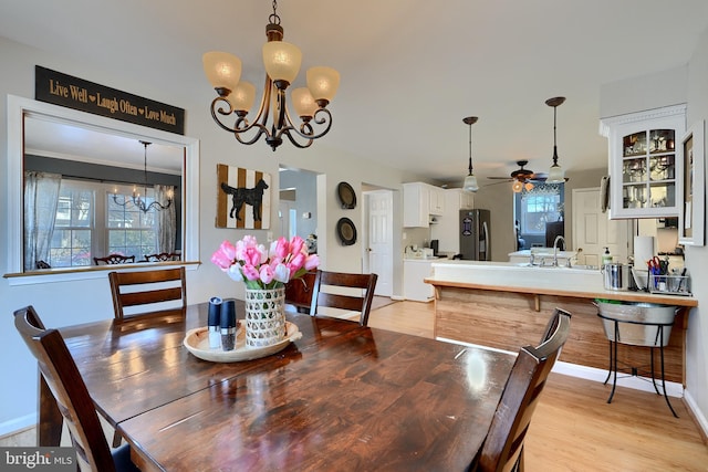 dining space featuring ceiling fan with notable chandelier, sink, and light hardwood / wood-style floors