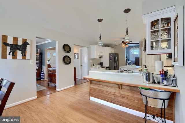 kitchen featuring sink, white cabinetry, stainless steel fridge with ice dispenser, light hardwood / wood-style flooring, and kitchen peninsula