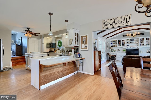 kitchen with vaulted ceiling with beams, white cabinetry, hanging light fixtures, appliances with stainless steel finishes, and kitchen peninsula