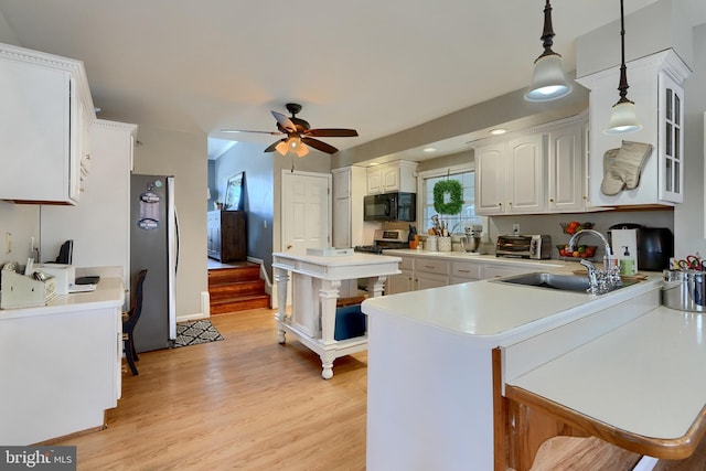 kitchen with sink, white cabinetry, stainless steel fridge, kitchen peninsula, and pendant lighting