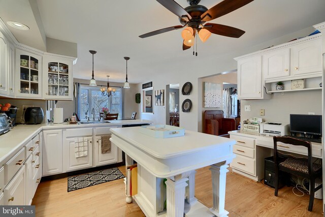 kitchen with hanging light fixtures, white cabinetry, sink, and light hardwood / wood-style floors