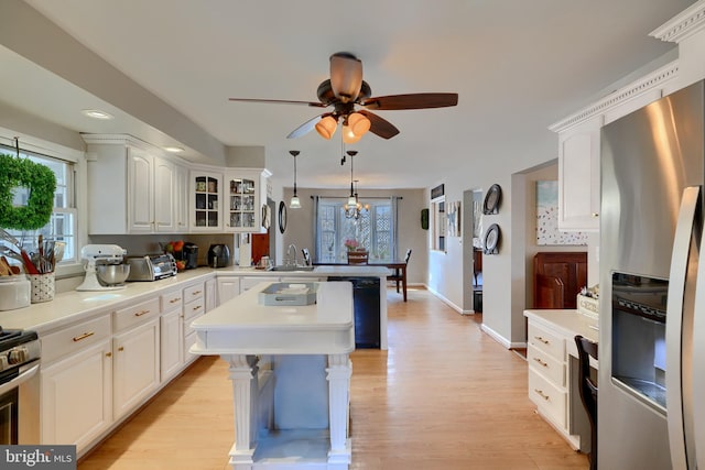 kitchen with sink, light hardwood / wood-style flooring, hanging light fixtures, stainless steel appliances, and white cabinets