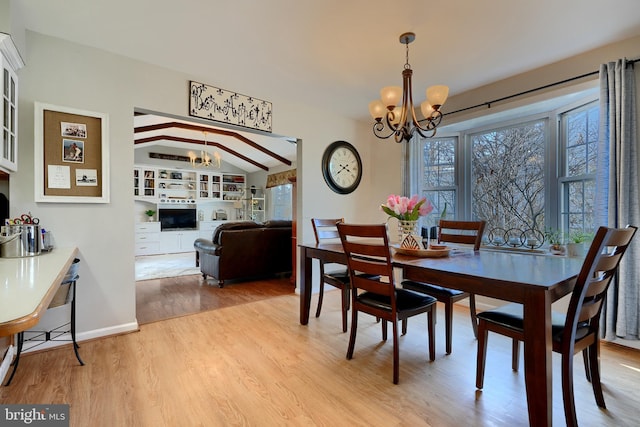 dining room with vaulted ceiling, light hardwood / wood-style floors, and a chandelier