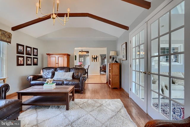 living room featuring lofted ceiling with beams, light hardwood / wood-style floors, and a chandelier