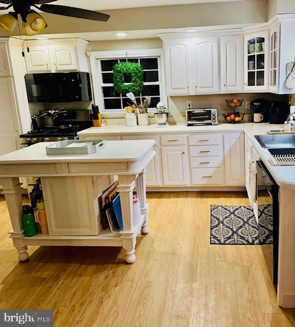 kitchen featuring ceiling fan, white cabinets, sink, and black appliances