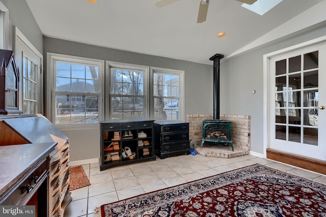 living room featuring light tile patterned flooring, ceiling fan, lofted ceiling, and a wood stove