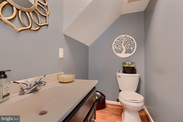 bathroom featuring vanity, hardwood / wood-style floors, lofted ceiling, and toilet