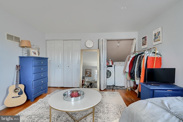 bedroom with hardwood / wood-style flooring, washing machine and clothes dryer, and a closet