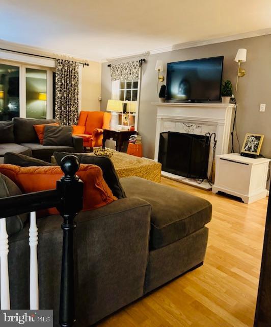 living room with crown molding, a premium fireplace, and hardwood / wood-style floors