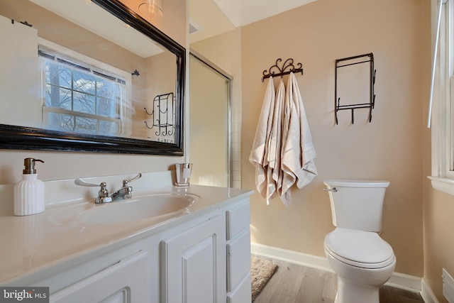 bathroom featuring wood-type flooring, walk in shower, vanity, and toilet