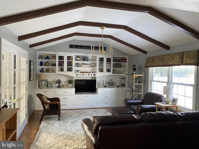 living room with lofted ceiling, light hardwood / wood-style floors, and french doors