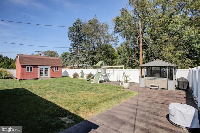 view of yard featuring a playground, an outbuilding, a hot tub, a gazebo, and a patio area