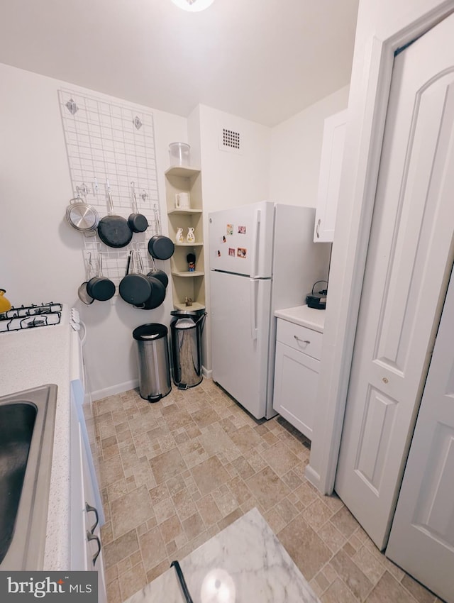 kitchen featuring white cabinetry, white refrigerator, and sink