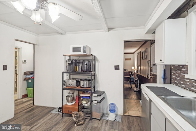 kitchen featuring sink, dishwasher, white cabinets, dark hardwood / wood-style flooring, and beamed ceiling