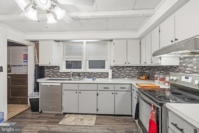 kitchen with appliances with stainless steel finishes, white cabinetry, beam ceiling, dark hardwood / wood-style floors, and tasteful backsplash