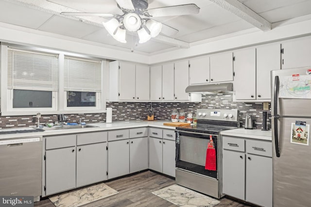 kitchen featuring beamed ceiling, appliances with stainless steel finishes, dark wood-type flooring, and backsplash