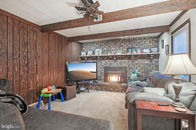 carpeted living room with beamed ceiling, a brick fireplace, and wood walls