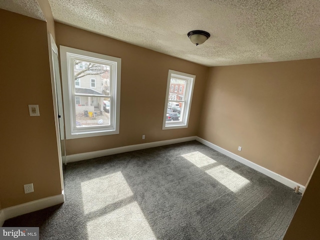 carpeted spare room with a textured ceiling and baseboards