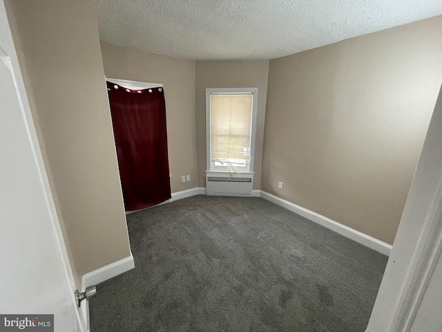 unfurnished bedroom featuring baseboards, dark colored carpet, and a textured ceiling