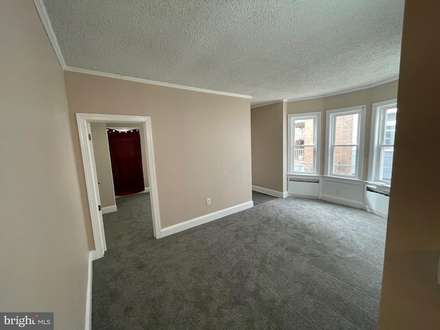 spare room featuring a textured ceiling, ornamental molding, dark carpet, and baseboards