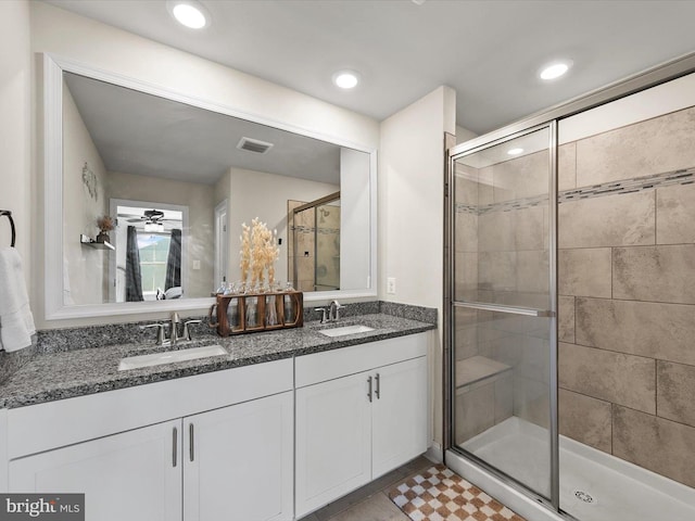 bathroom with vanity, a shower with shower door, and ceiling fan