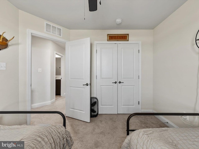 bedroom featuring light colored carpet, a closet, and ceiling fan