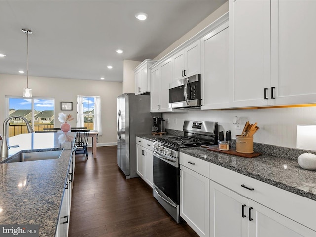 kitchen with sink, dark stone counters, pendant lighting, stainless steel appliances, and white cabinets