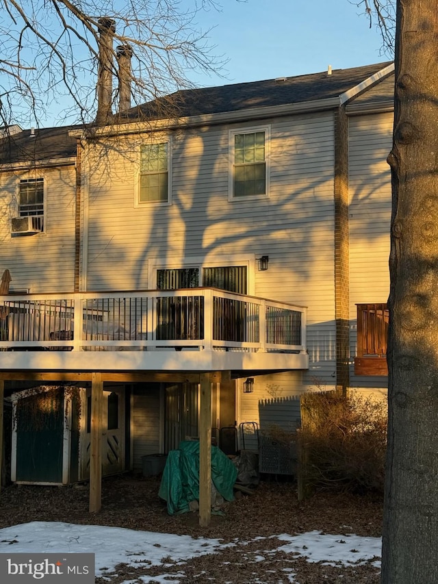 snow covered back of property with a deck